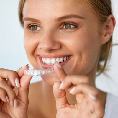woman smiling and holding a clear aligner