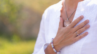 close up of woman with hand on heart
