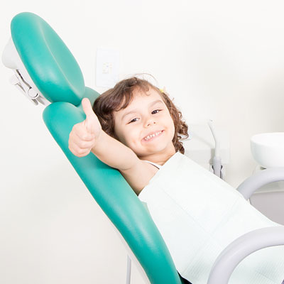 Little girl giving thumbs up in dental chair