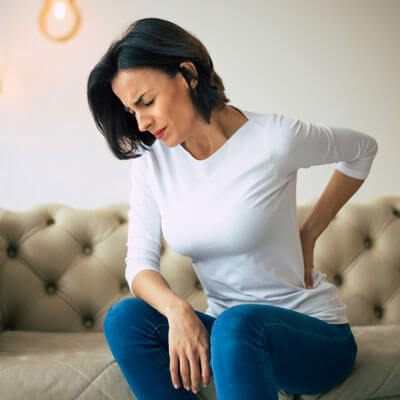 Woman with low back pain sitting on couch