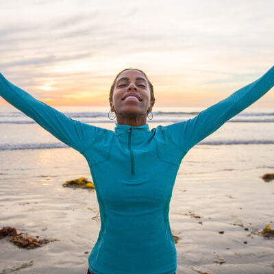 Woman with arms stretched up on beach